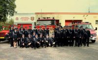 Zdjęcie: Strażacy ochotnicy stojący przed remizą strażacką